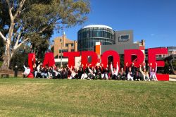 Students sitting on the lawn in front of La Trobe Letters on campus.