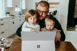 A man on a laptop with kids on his lap