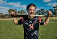 La Trobe Sport student holding hockey stick and smiling at the camera