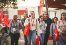 La Trobe students at Orientation week walking across the campus, smiling and wearing La Trobe branded tote bags.