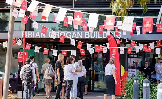 Students at Mildura o Week with red and white flags hanging above the pathway