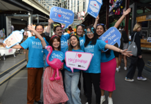 Students wearing blue t shirts happily posing for a photo in the City of Melbourne