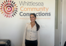 La Trobe student Emily standing in front of the Whittlesea Community Connections sign