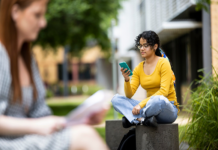 Student in yellow jumper using smartphone